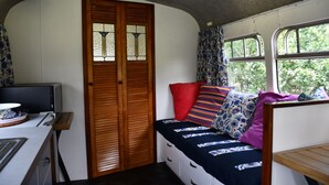A compact room with a bed, a desk, and a window. - Evi the school bus at Oromahoe Downs Farm (Kerikeri)