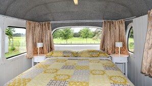 A compact bedroom with a bed, two bedside tables, and curtains. - Evi the school bus at Oromahoe Downs Farm (Kerikeri)