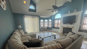A living room with a curved sectional sofa, a fireplace, and a television. - Nautical SIC haven: 4BR + Bonus Room in the Heart of SIC (Sea Isle City)