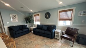 A living room with two dark sofas, a coffee table, a side table, a leather chair, and a potted plant.