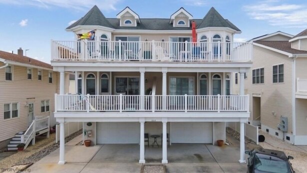 Une maison à deux étages avec un balcon, un garage et une allée.