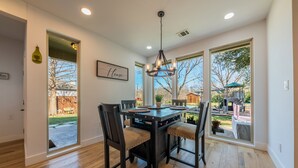 A dining area with a wooden table, four chairs, and a chandelier. - Modern luxury home - on 1/2 acre near Kalahari (Hutto)