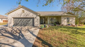 A single-story house with a garage, a front porch, and a well-maintained lawn. - Modern luxury home - on 1/2 acre near Kalahari (Hutto)