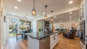 A spacious kitchen with a central island, overhead pendant lights, and a view of the backyard. - Modern luxury home - on 1/2 acre near Kalahari (Hutto)