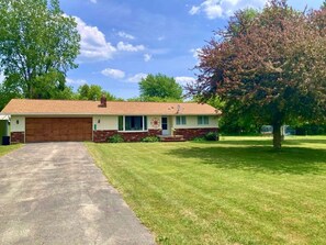 A single-story house with a garage, a front lawn, and a large tree. - NO CLEANING FEES for 2025!! CLOSE TO BEACH!! Pet-Friendly! (Carsonville)