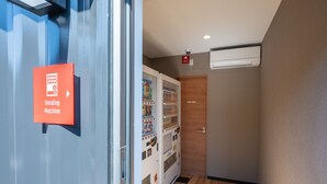 Un pasillo con máquinas expendedoras, un letrero que dice 'Vending Machine' y una puerta para personal autorizado.