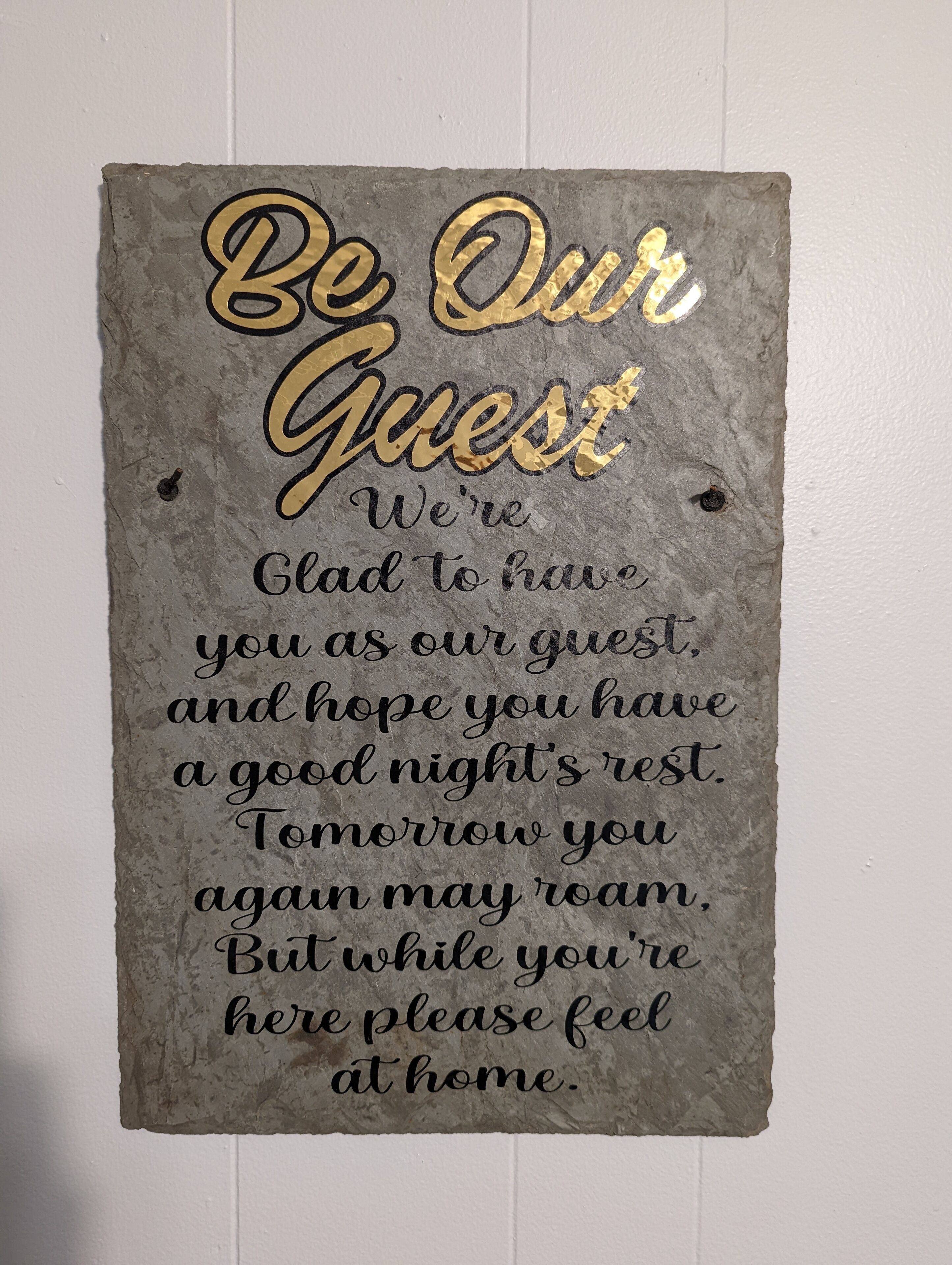 Ein Schild mit einer Botschaft für Gäste, an einer Wand befestigt.