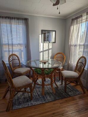 A dining area with a round glass table surrounded by four wicker chairs, a patterned rug, and a ceiling fan. - Mountain Views, River fun, Hiking, Biking, Breweries, Golf, and Wineries galore (Jonesville)