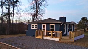A small, single-story house with a wooden deck and a gravel driveway. - Mountain Views, River fun, Hiking, Biking, Breweries, Golf, and Wineries galore (Jonesville)