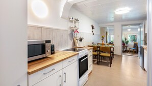 Une cuisine moderne équipée d’un four à micro-ondes, d’un four et d’un plan de travail en bois. On y trouve également un coin repas avec des chaises et une table.