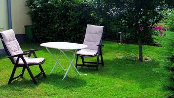 Ein Sitzbereich im Freien mit zwei Stühlen und einem Tisch, umgeben von Gras und Pflanzen.