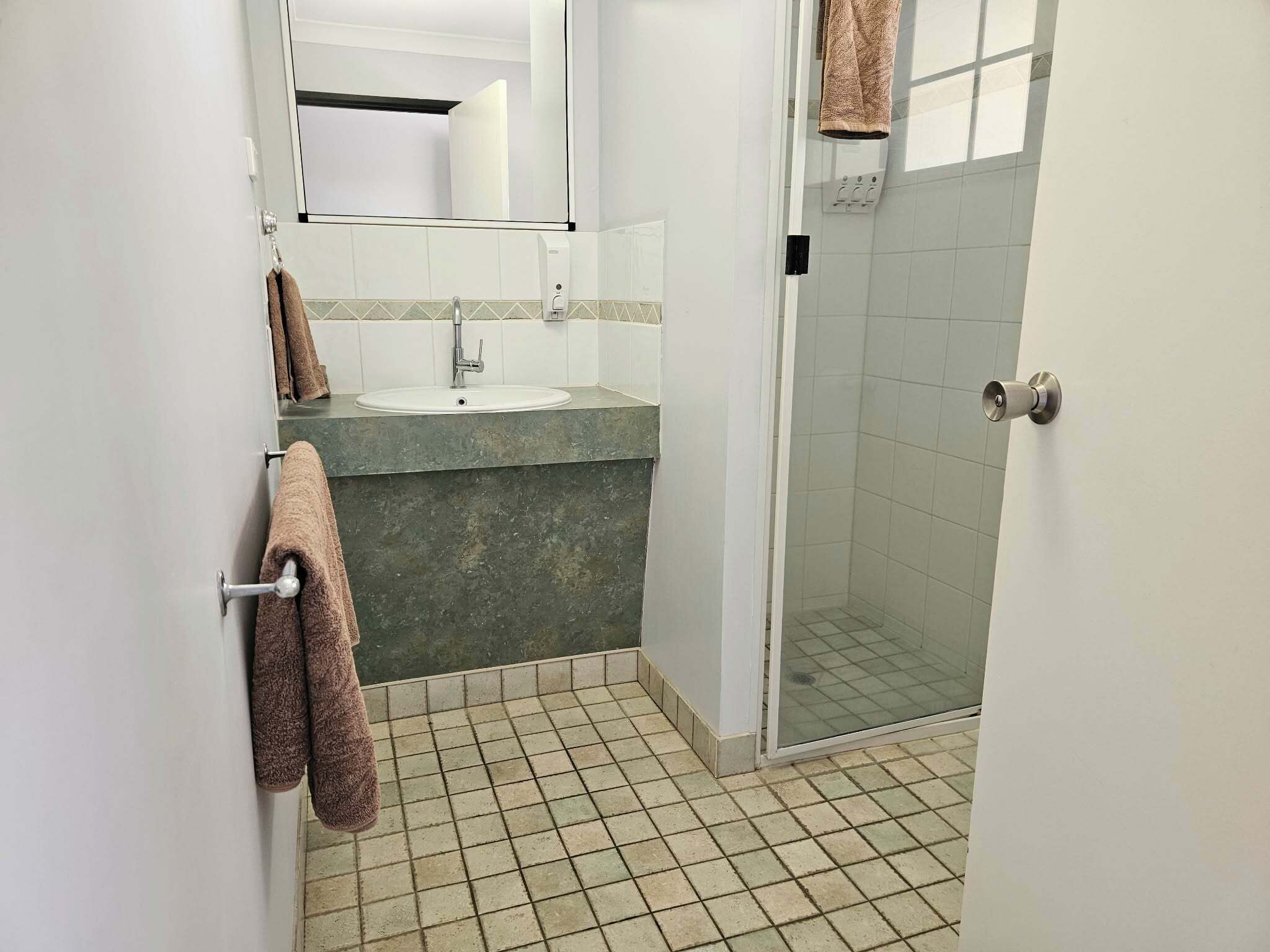 Ein Badezimmer mit Waschbecken, Spiegel und Dusche.