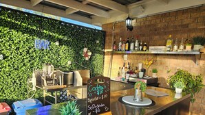 Zona de bar con una pared verde, un menú en pizarra y varias botellas.