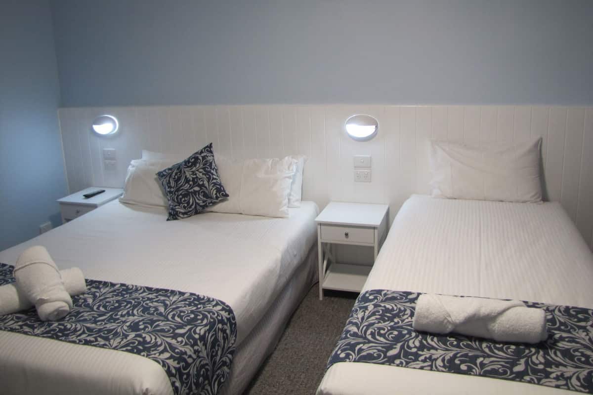 Een hotelkamer met twee bedden, elk met een kussen en een nachtkastje.