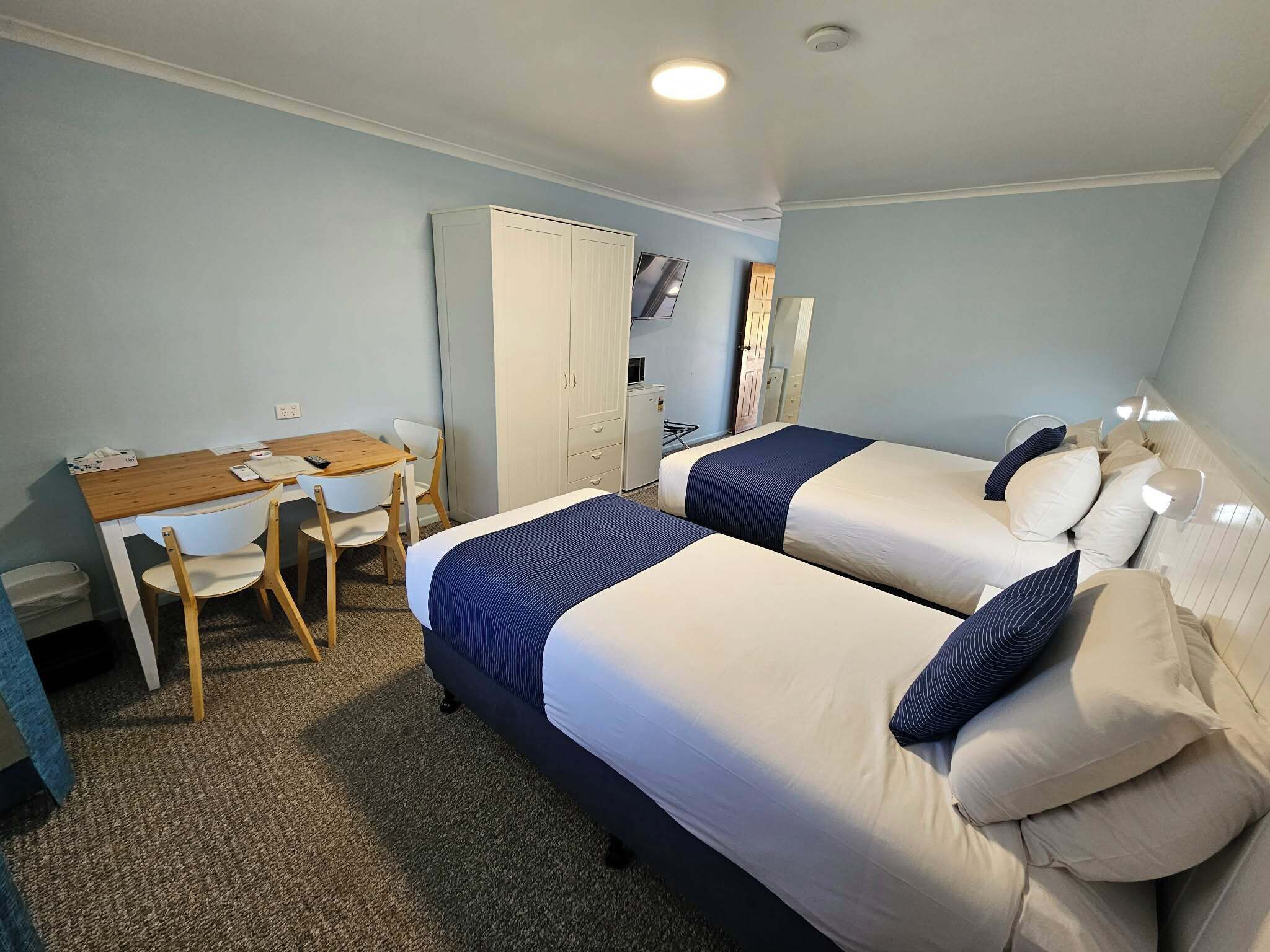 Een kamer met twee bedden, een bureau en een kledingkast.