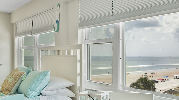 Ein Zimmer mit einem Bett, einem runden Tisch und Blick auf den Strand.
