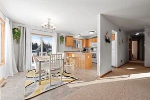 A modern kitchen with wooden cabinets, a central island, and a dining area with a table and chairs. - Cozy Home- 2 King/ 2 Queen , 5 minutes to DT St. Paul (Saint Paul)