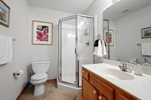 A modern bathroom with a toilet, a glass-enclosed shower, and a vanity with a sink and mirror. - Cozy Home- 2 King/ 2 Queen , 5 minutes to DT St. Paul (Saint Paul)