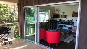 Um deck de madeira com uma porta de correr de vidro que dá para um espaço interno.