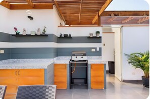 A modern kitchen with a built-in oven, a sink, and a countertop. There are shelves above the counter with decorative items.
