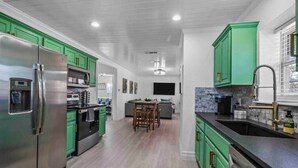 Una cocina moderna con gabinetes verdes, electrodomésticos de acero inoxidable y una isla central.