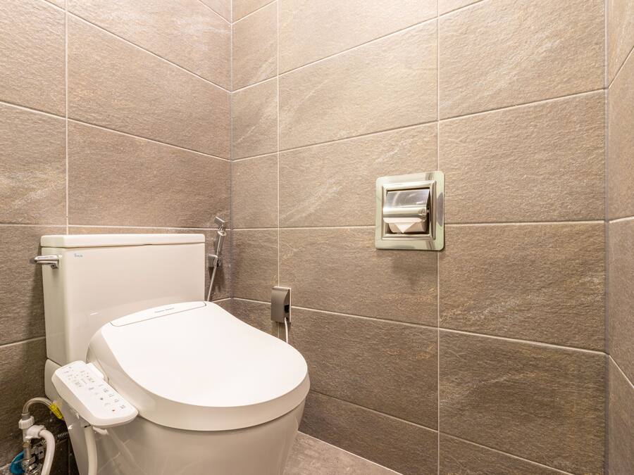 A modern bathroom with a toilet, a bidet, and a wall-mounted bidet.