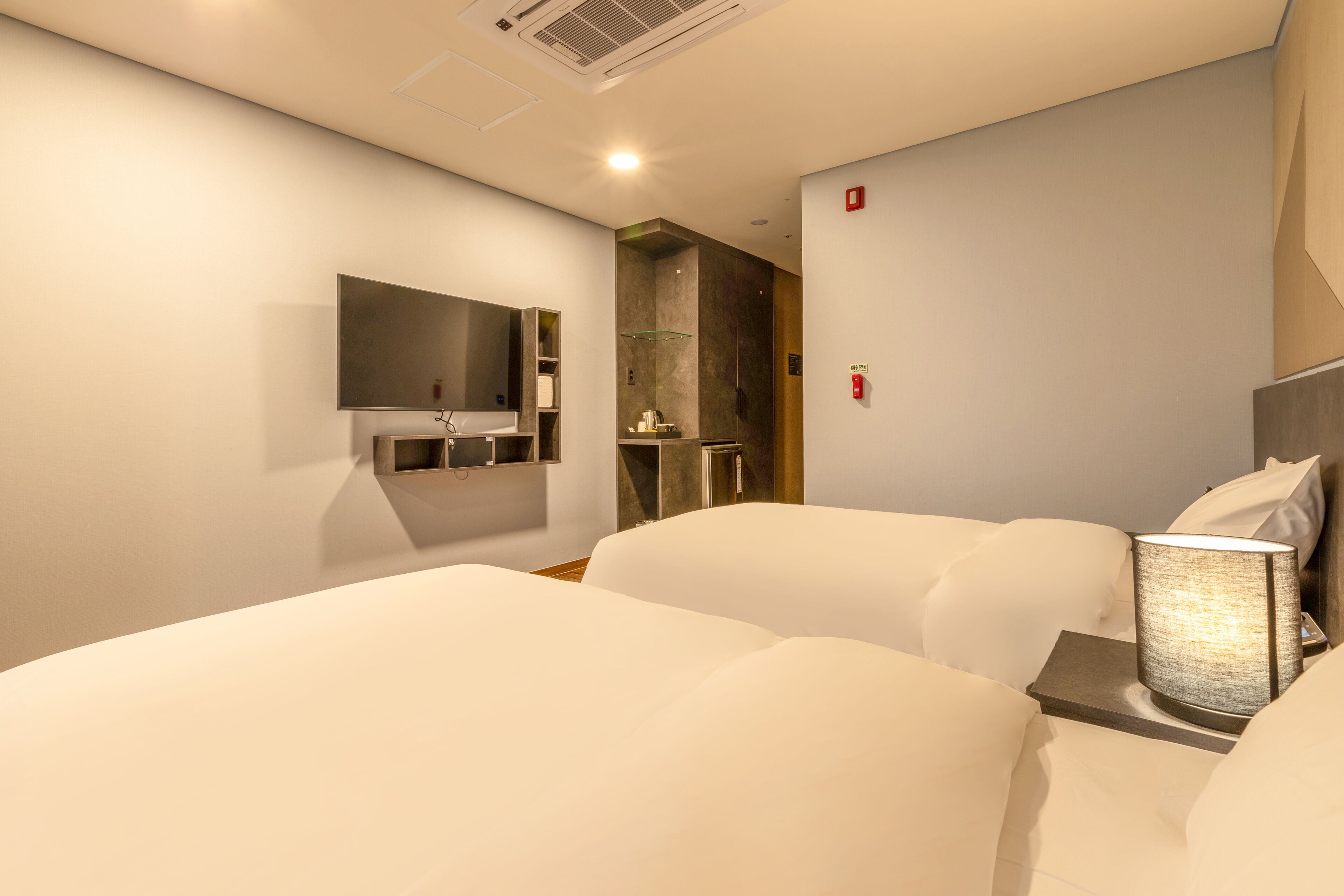 A hotel room with two beds, a bathroom, and a small kitchenette.