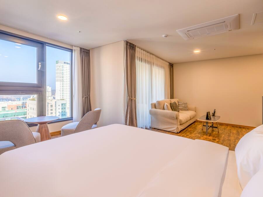 Une chambre d’hôtel avec un grand lit, un canapé, une petite table et une fenêtre avec des rideaux.