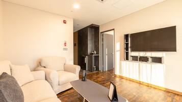 A modern living room with a sofa, a coffee table, and a flat-screen TV mounted on the wall.