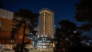 Ein hohes Hotel mit mehreren Stockwerken, umgeben von Bäumen und anderen Gebäuden.