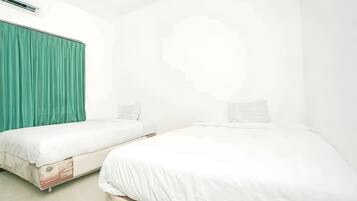 Una habitació d'hotel amb dos llits individuals, una cortina verda i una paret blanca.