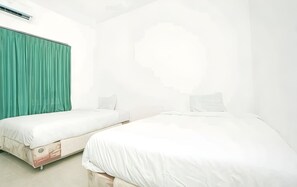 A hotel room with two single beds, a green curtain, and a white wall.