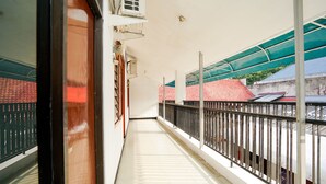 A corridor with a metal railing, a tiled floor, and a view of buildings with red roofs.