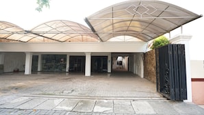 A building with a covered entrance, large glass windows, and a paved walkway.