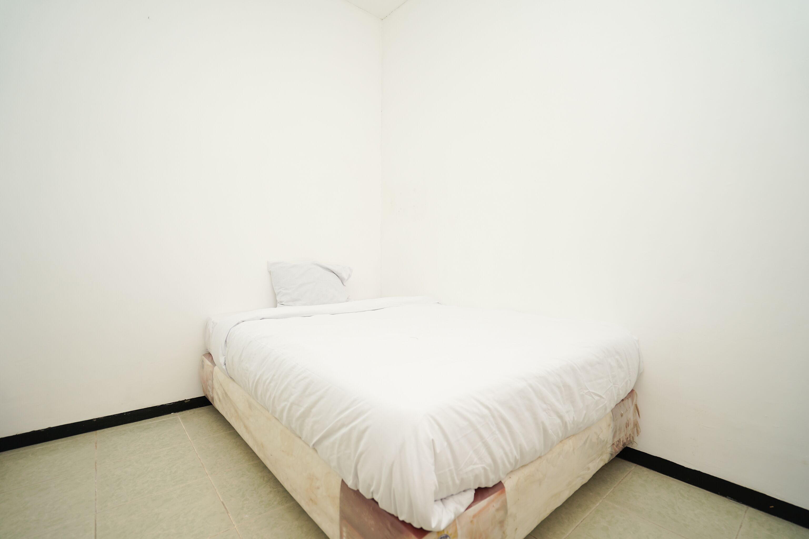 A small, single-bed room with white bedding and a wooden headboard.