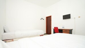 A hotel room with two beds, a desk, a chair, a TV, and a door.