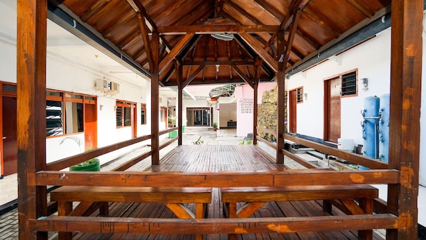 A covered wooden deck with benches, white walls, and a view of the street.