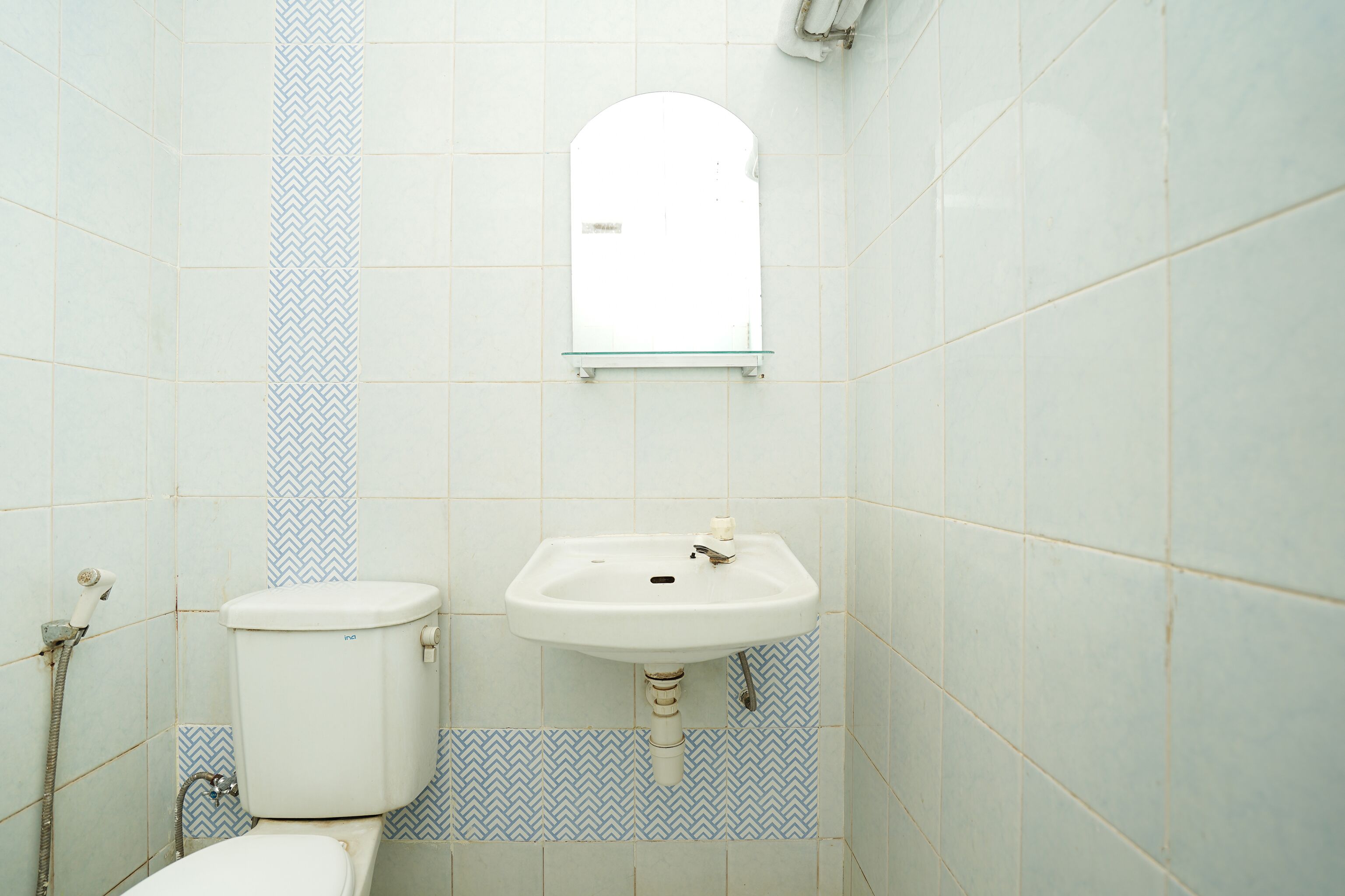 A bathroom with a toilet, sink, and mirror.