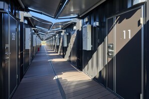 A corridor with numbered doors, likely indicating hotel rooms, and a wooden floor. - HOTEL R9 The Yard Higashiomi (Higashiomi)