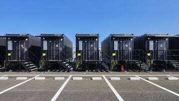 A row of identical black modular units with numbered doors, each with a small staircase leading to the entrance.