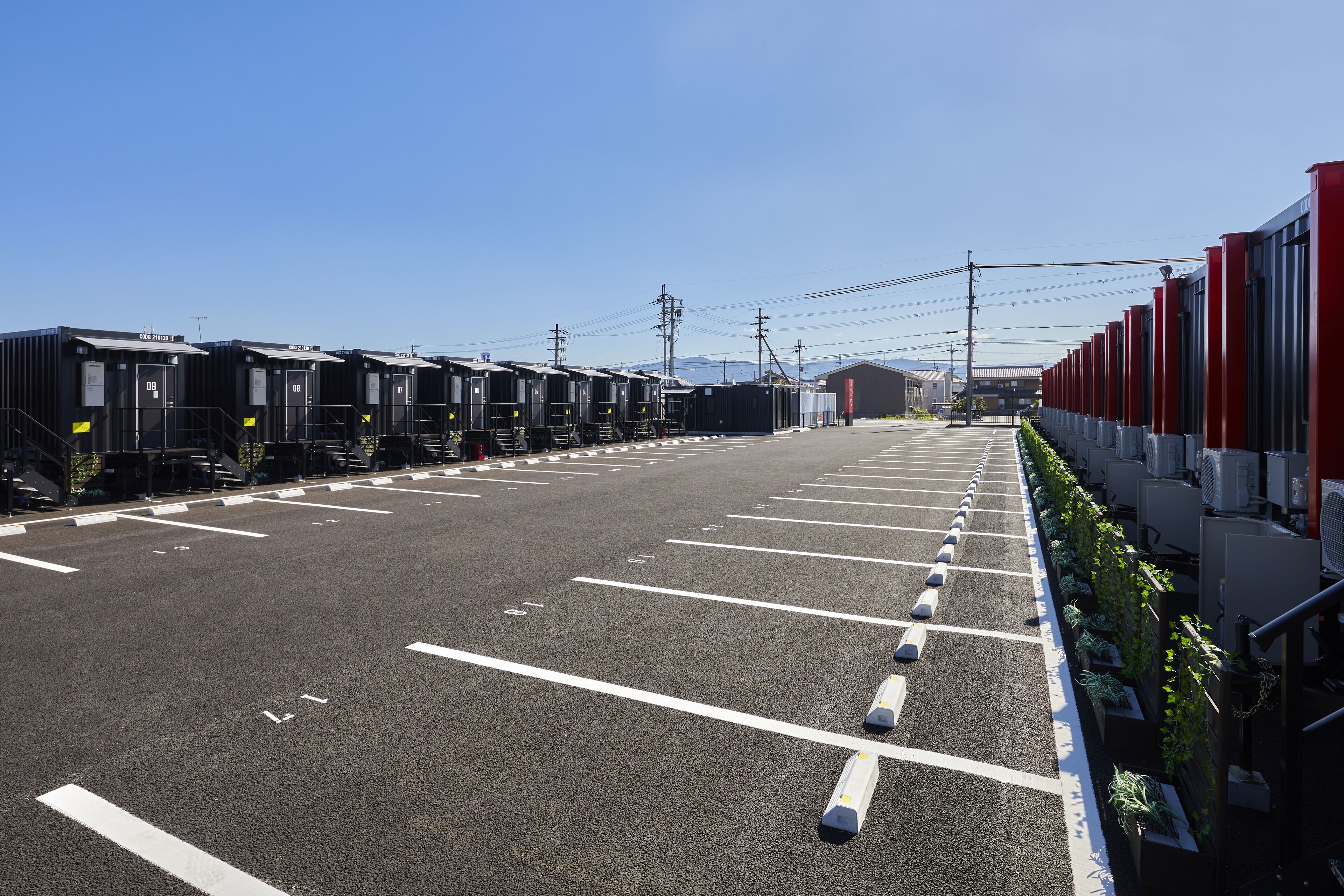 Un estacionamiento con filas de trenes estacionados y una hilera de edificios rojos a la derecha.