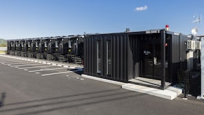 A row of black modular units with a clear entrance, labeled "CODQ 210102," in a parking lot. - HOTEL R9 The Yard Higashiomi (Higashiomi)