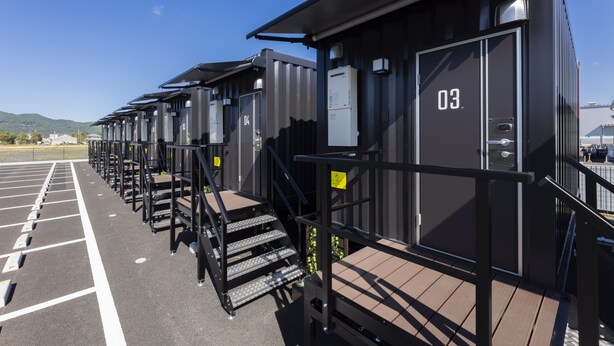 A row of identical modular cabins with numbered doors, each with a small outdoor deck and a staircase leading to the deck. - HOTEL R9 The Yard Higashiomi (Higashiomi)