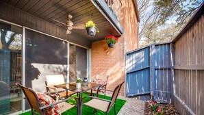 A patio with a table and chairs, a hanging planter with flowers, and a blue fence. - 1st Flr Luxury2b 2bth Condo w/King/2 sep twin beds (Grand Prairie)