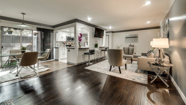 A modern living room with dark wood flooring, a glass dining table, and contemporary furniture. - 1st Flr Luxury2b 2bth Condo w/King/2 sep twin beds (Grand Prairie)