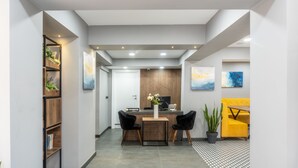 A modern interior with a reception desk, seating area, and decorative plants.