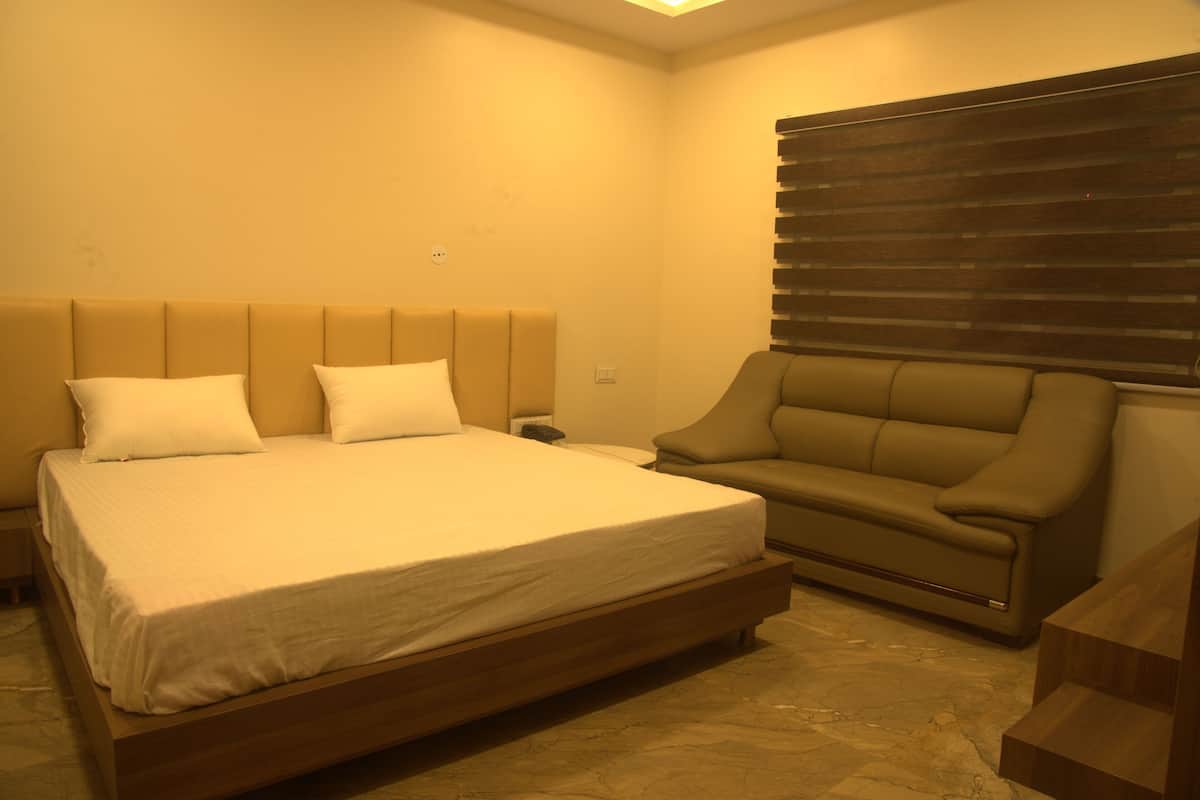 Un dormitorio con una cama grande, un sofá y una ventana con persianas.