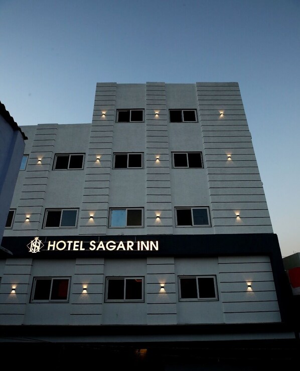 A multi-story hotel with a modern facade, featuring evenly spaced windows and a prominent sign reading "HOTEL SAGAR INN".