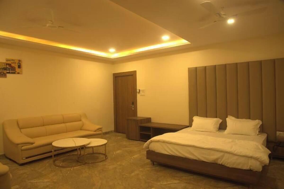Un dormitorio moderno con cama, sofá, una mesita redonda y una puerta.