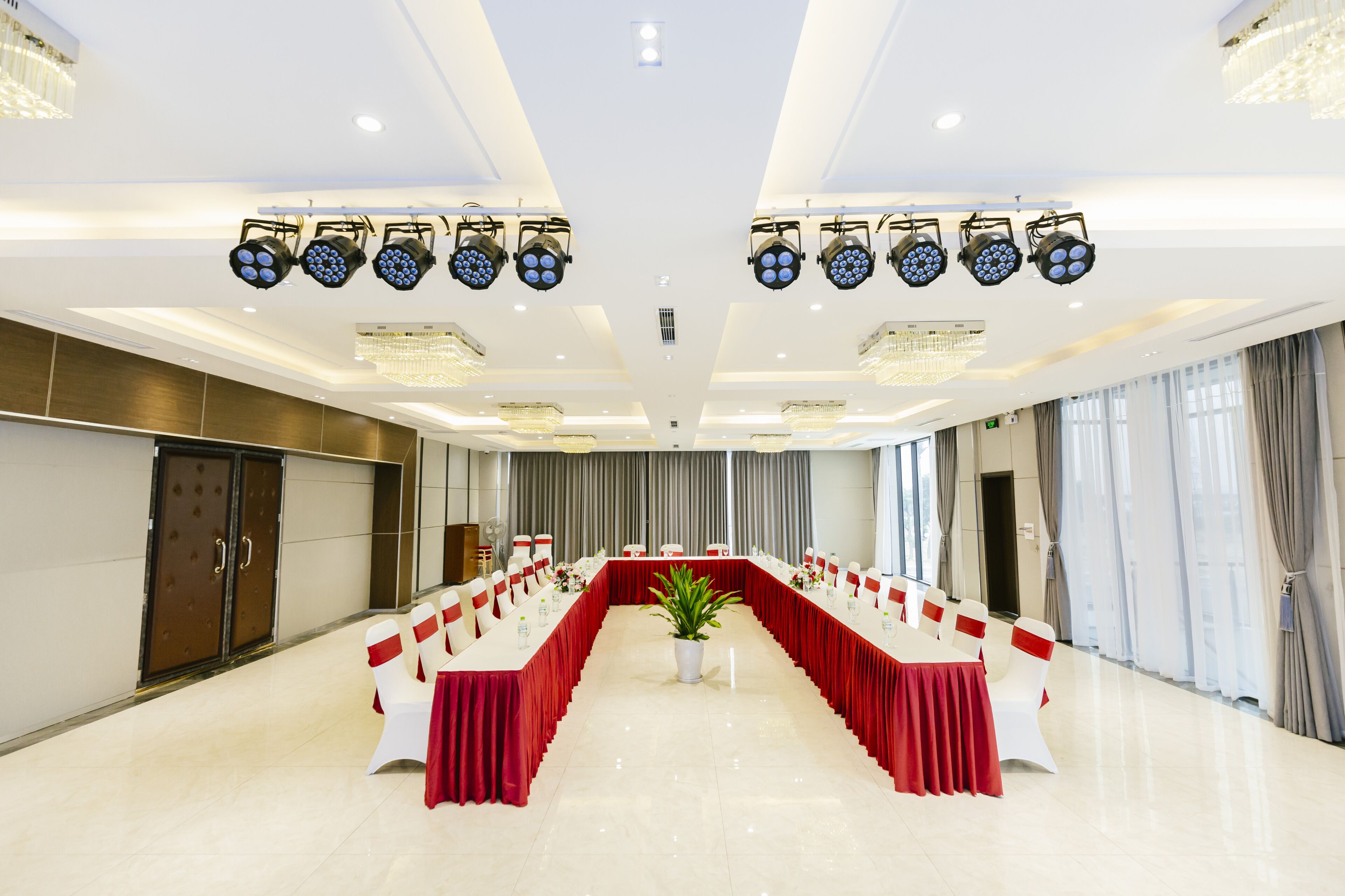 A conference room with a long table, white chairs, and red tablecloths.